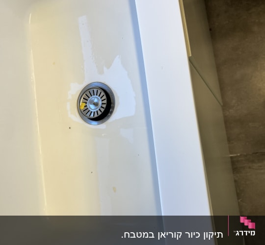 כיור שיש לבן עם פתח ניקוז מתכתי